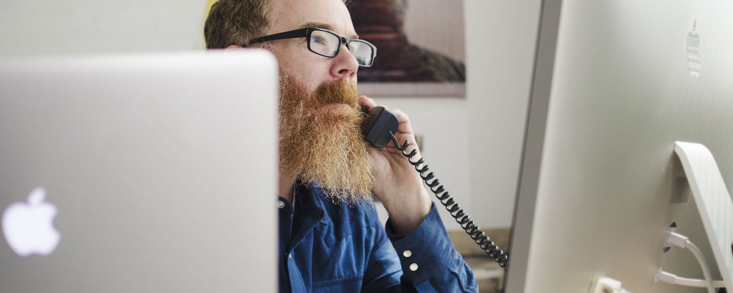 A man working at his computer on the phone